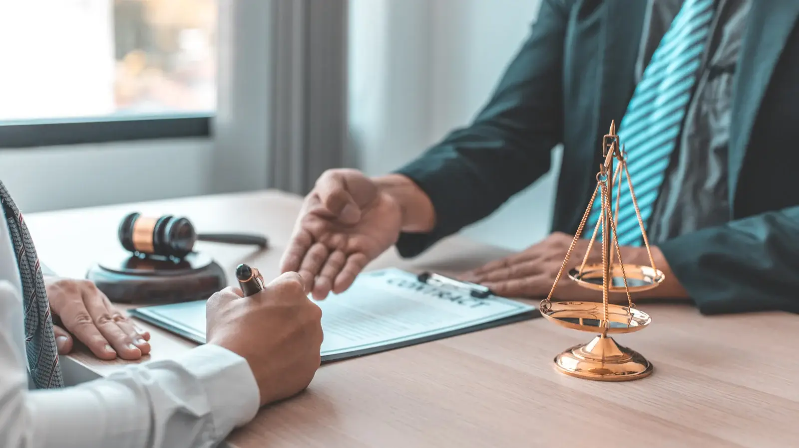 Consultation juridique entre un avocat et un entrepreneur signant un document, avec une balance de la justice et un marteau en arrière-plan.