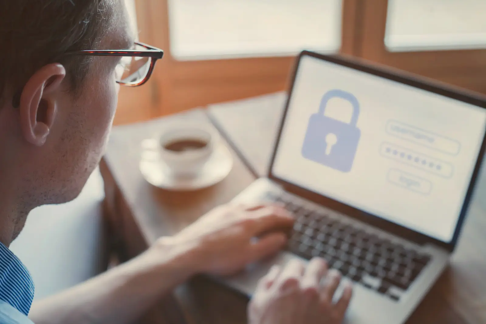Homme utilisant un ordinateur avec un écran affichant un cadenas et un formulaire de connexion, symbolisant la protection des données et la conformité RGPD.